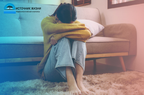 Девушка сидит на полу, опустив голову на колени